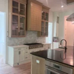 Custom kitchen island with dark countertop, light cabinetry, and modern appliances in a stylish kitchen setting.