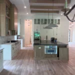 Custom kitchen island with modern cabinetry, light wood flooring, and pendant lighting in a spacious kitchen setting.