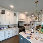 Modern kitchen featuring custom cabinetry, white cabinets, a large island with a light countertop, and stylish pendant lighting, showcasing a functional and aesthetic kitchen design by The Perfect Cabinet.