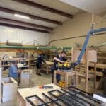 Cabinet makers working in a woodworking shop, showcasing custom cabinetry craftsmanship and tools in use.