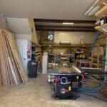 Cabinetry workshop interior with tools, wood materials, and equipment for custom cabinetry projects.