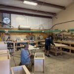 Cabinet makers working in a workshop, constructing custom cabinetry with tools and materials, showcasing craftsmanship for The Perfect Cabinet Shop.