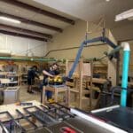 Workshop interior showing craftsmen working on custom cabinetry projects, featuring tools and wood materials, highlighting The Perfect Cabinet Shop's craftsmanship.