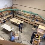 Woodworking shop with craftsmen working on custom cabinetry projects and tools, illustrating The Perfect Cabinet Shop's craftsmanship and services.
