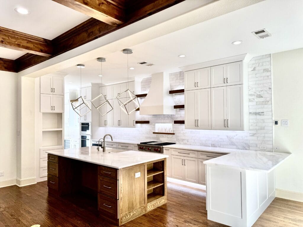 Modern kitchen with white cabinetry, marble countertops, wooden beams, and pendant lighting, showcasing a stylish design ideal for home remodeling and kitchen renovations.