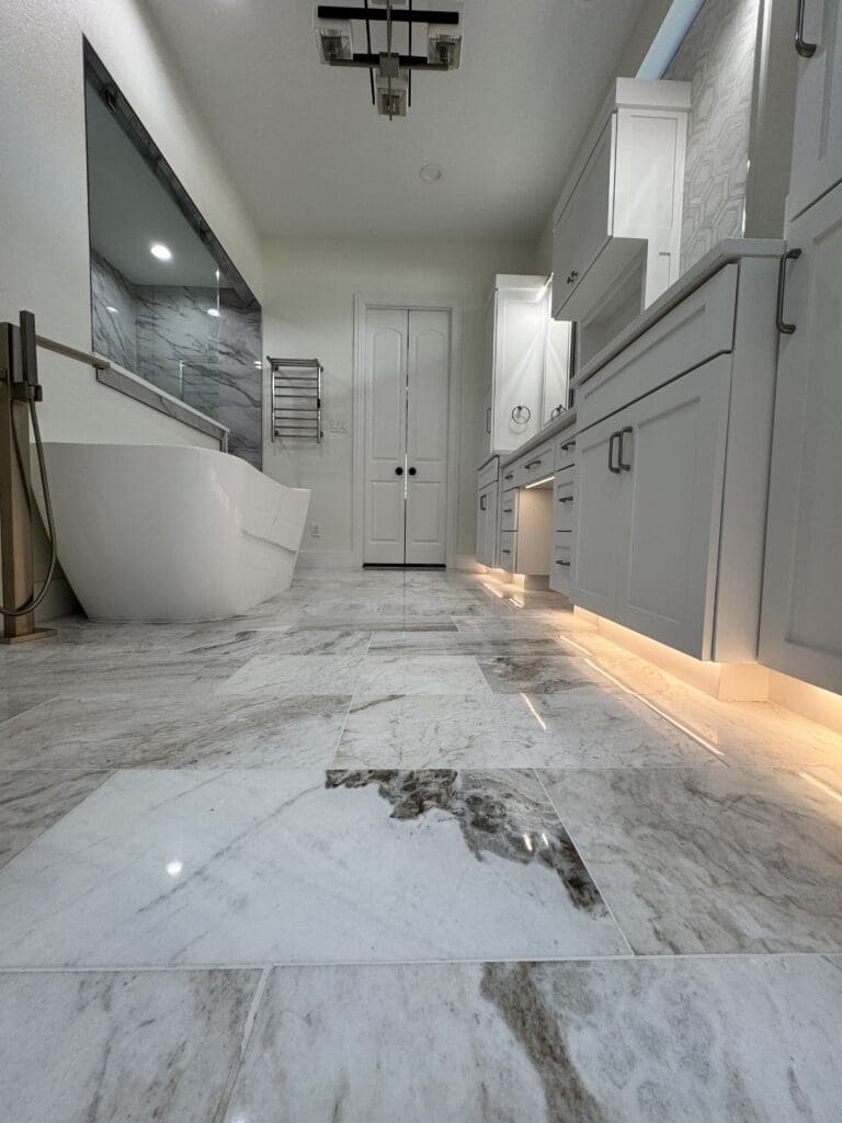 Modern bathroom interior featuring a freestanding bathtub, elegant cabinetry, marble flooring, and contemporary lighting, showcasing home remodeling design by The Perfect Cabinet Company in Dallas.