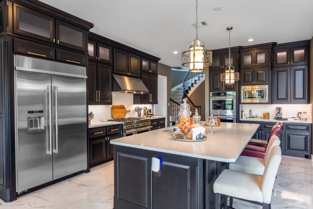 Modern kitchen featuring dark cabinetry, stainless steel appliances, and a large island with seating, showcasing custom cabinetry and design elements relevant to home remodeling services.