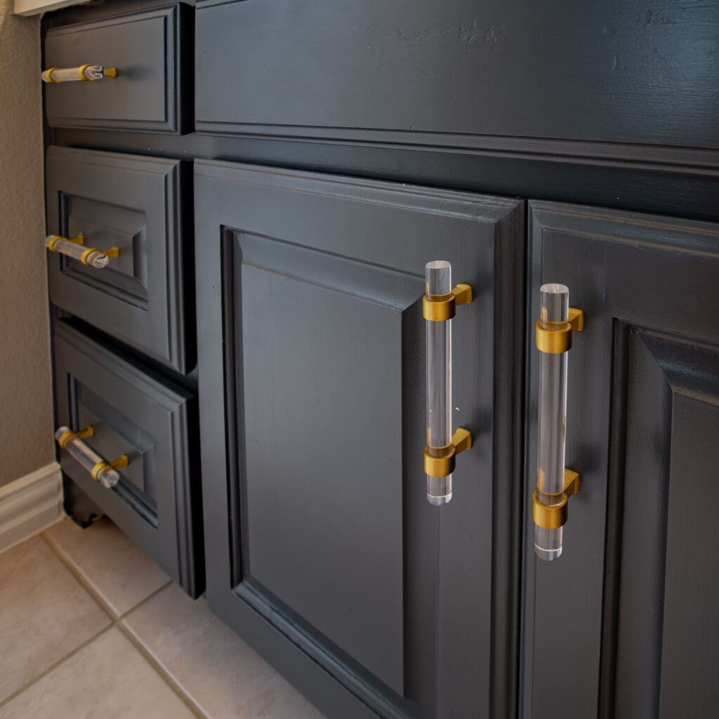 Modern dark cabinetry with gold and clear acrylic handles, showcasing custom design elements for kitchen or bathroom remodeling.