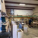 Cabinet makers working on custom cabinetry in a workshop, showcasing craftsmanship and woodworking tools.