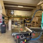 Workshop interior with woodworking equipment, including a table saw, showcasing craftsmanship for custom cabinetry at The Perfect Cabinet Shop.