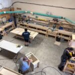Woodworkers assembling custom cabinetry in a workshop, showcasing craftsmanship and tools used in cabinetry projects.