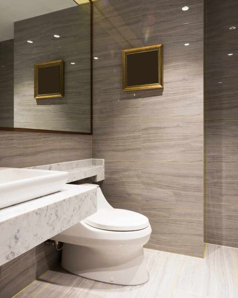Modern bathroom featuring a sleek white toilet, minimalist marble countertop, and elegant gray stone walls, reflecting luxury design trends in Dallas home renovations.