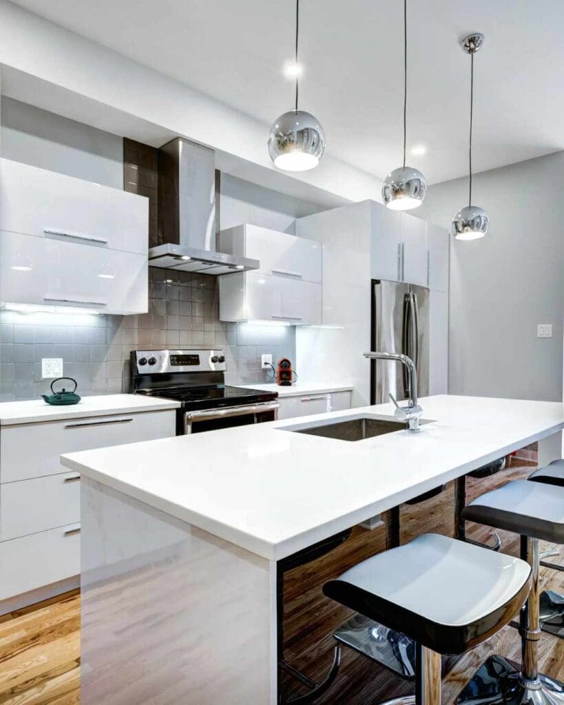 Modern kitchen design featuring sleek white cabinets, stainless steel appliances, and a spacious island with bar stools, emphasizing home remodeling and custom cabinetry by The Perfect Cabinet Company.