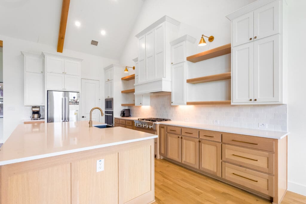 Modern kitchen featuring custom cabinetry, a large island with a light wood finish, stainless steel appliances, and open shelving, showcasing a bright and spacious design ideal for home remodeling inspiration.