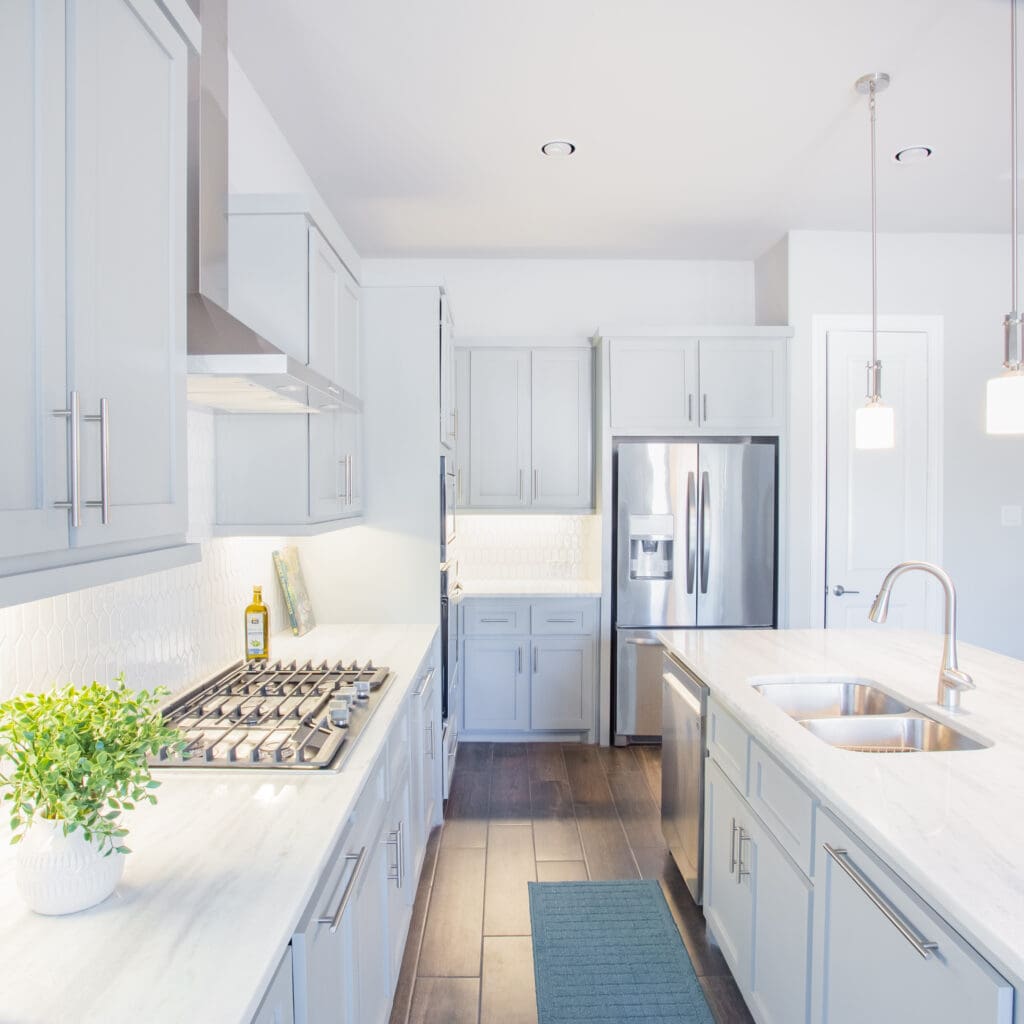 Modern kitchen featuring light gray cabinetry, stainless steel appliances, gas stove, marble countertops, and a contemporary design, ideal for home remodeling inspiration.