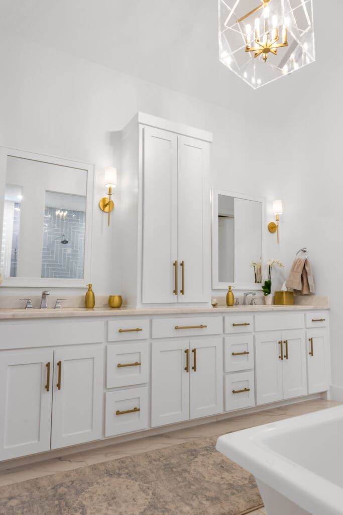Modern bathroom design featuring white cabinetry, gold hardware, and stylish lighting fixtures, showcasing custom cabinet work by The Perfect Cabinet Company.