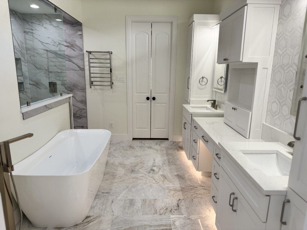 Modern bathroom featuring a freestanding white tub, double sink vanity with marble countertops, elegant cabinetry, and a glass shower, showcasing a luxurious remodel ideal for small spaces.