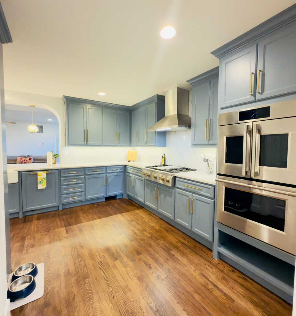 Modern kitchen with blue cabinetry, stainless steel appliances, and hardwood flooring, showcasing efficient design for small spaces.