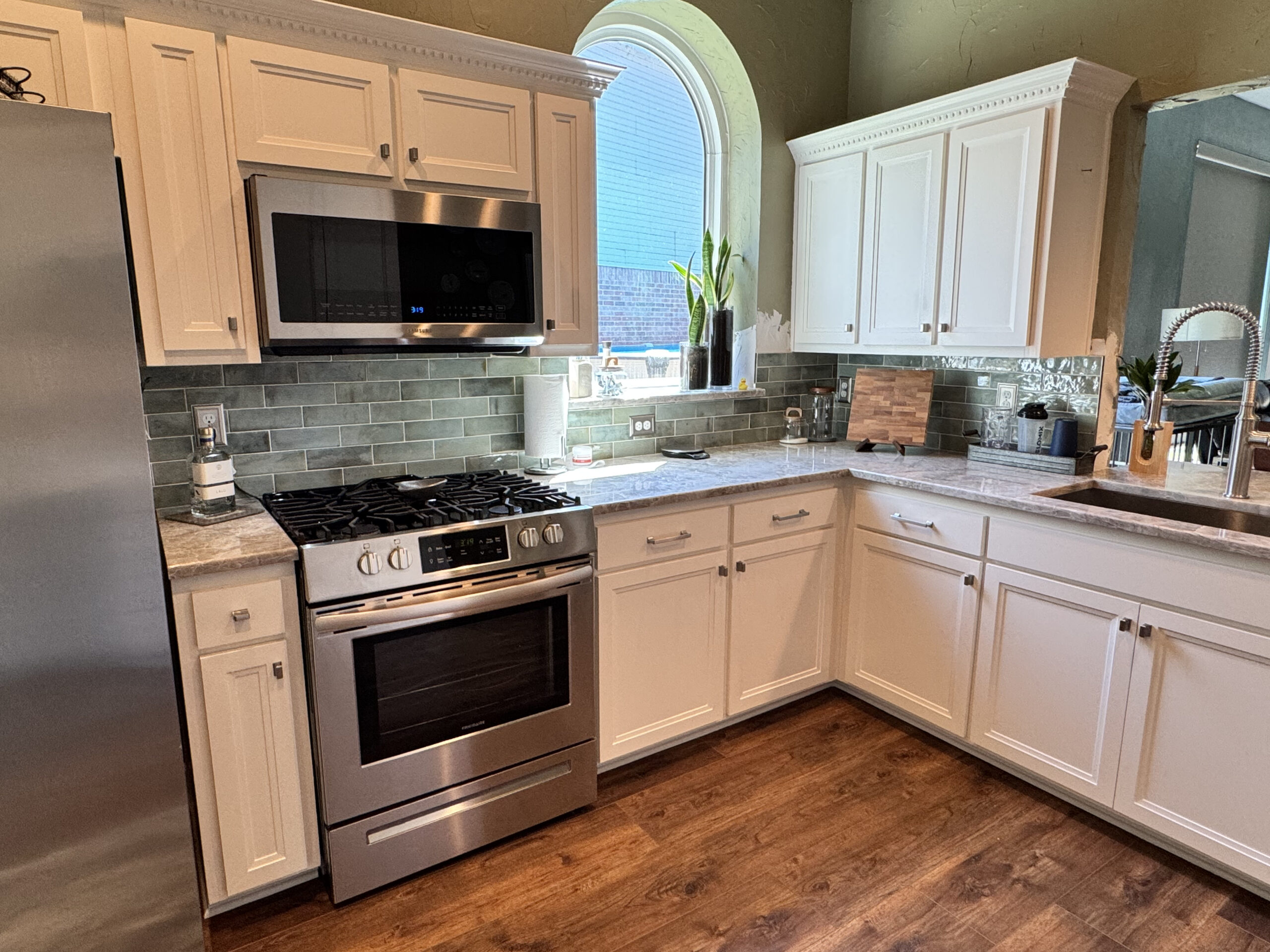 Modern kitchen featuring white cabinetry, stainless steel appliances, and a granite countertop, highlighting efficient kitchen design and custom cabinetry solutions for remodeling.