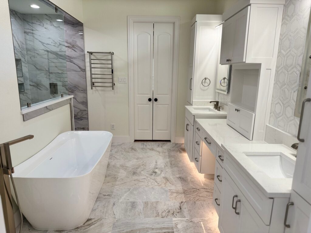 Luxurious modern bathroom featuring a freestanding tub, dual sinks with white cabinetry, marble flooring, and a glass-enclosed shower, reflecting high-end remodeling trends in Collin County and DFW.