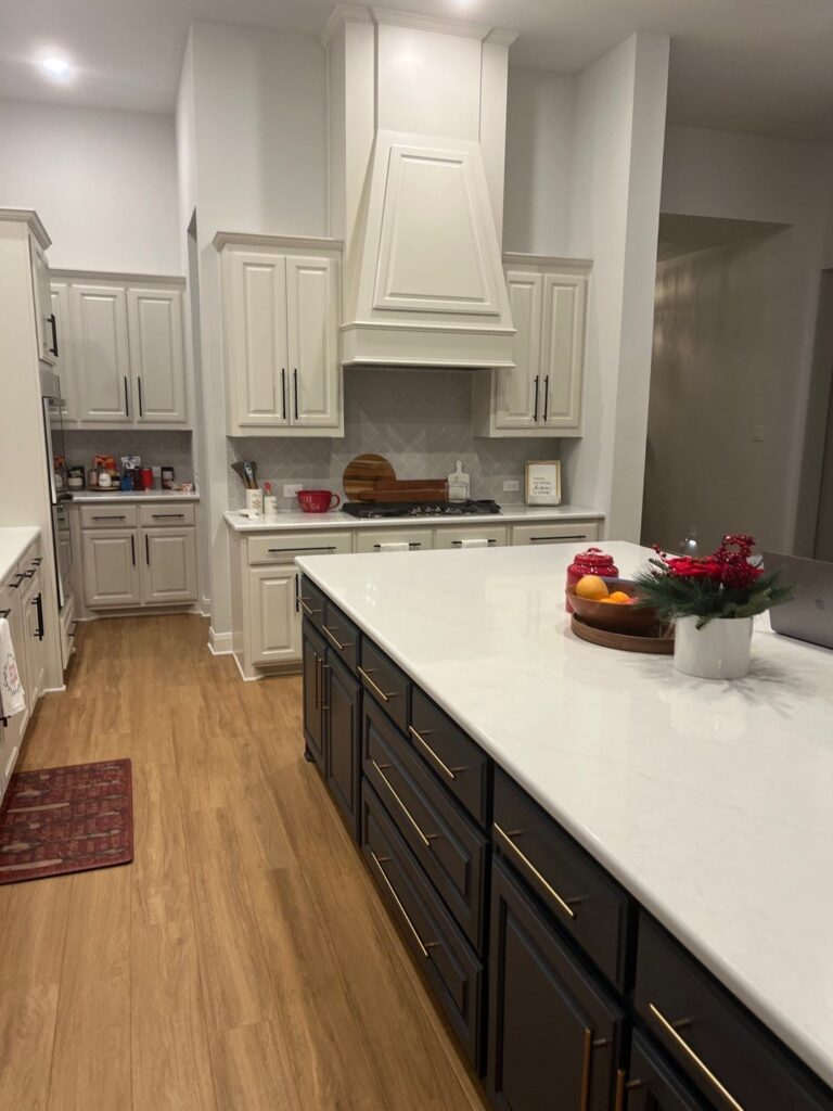 Modern kitchen interior featuring white cabinetry, dark island with gold hardware, and a spacious layout, emphasizing functionality and style for remodeling inspiration in Collin County and DFW.