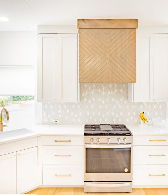 Modern kitchen design featuring white cabinetry, a stainless steel stove, and a wooden range hood, emphasizing craftsmanship and style for kitchen remodeling inspiration.