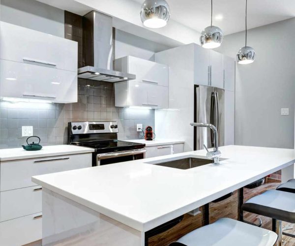 Modern kitchen design featuring sleek white cabinetry, stainless steel appliances, quartz countertop, and pendant lighting in a bright, functional layout.