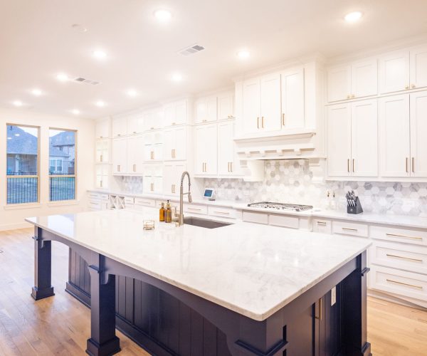Modern kitchen featuring custom white cabinetry, a large marble island, premium countertops, and stylish hexagonal backsplash, designed for functionality and aesthetics in a bright, open space.