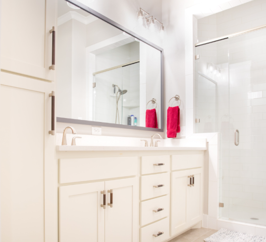 Modern bathroom featuring a white quartz countertop with dual sinks, a large mirror, and sleek cabinetry, complemented by red towels, emphasizing luxury and functionality in bathroom design.