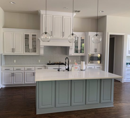 Modern kitchen featuring white Shaker cabinets, a light gray island, quartz countertops, pendant lighting, and a contemporary backsplash, reflecting popular remodeling trends in Collin County.