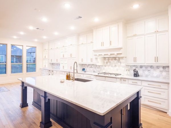 Modern kitchen design featuring white cabinetry, a large marble island, and stylish fixtures, showcasing custom cabinetry and premium countertops by The Perfect Cabinet Company in Aubrey, TX.