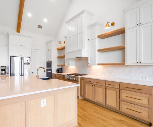 Modern kitchen featuring custom cabinetry, high-quality countertops, and contemporary lighting, showcasing a spacious layout with soft-close drawers, open shelving, and stainless steel appliances.
