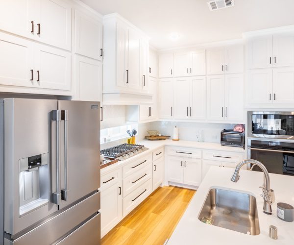 Modern kitchen featuring white cabinetry, stainless steel appliances, and a spacious layout with a sink and countertop, showcasing high-quality craftsmanship for remodeling projects by The Perfect Cabinet Company in Fairview, TX.