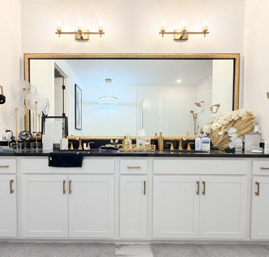 Modern bathroom vanity with white cabinetry, black countertop, integrated lighting, and decorative accessories, reflecting custom design elements for optimized space and functionality.