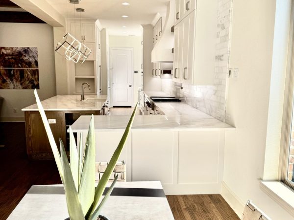 Modern kitchen design featuring white cabinetry, marble countertops, and a stylish pendant light, showcasing a functional and aesthetically pleasing culinary space ideal for kitchen remodeling in Bedford, TX.
