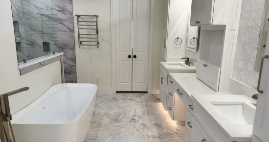 Modern bathroom featuring a freestanding white bathtub, dual sinks with sleek cabinetry, and marble flooring, illustrating high-end design elements for a kitchen remodel.