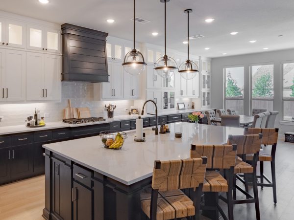 Modern kitchen design featuring custom cabinetry, a large island with wood-accented bar stools, pendant lighting, and a bright, spacious layout with natural light.