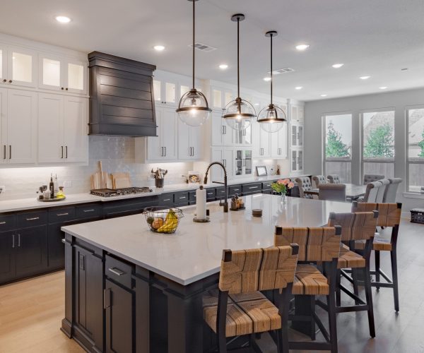 Modern kitchen design featuring a large island with bar stools, sleek cabinetry in black and white, pendant lighting, and a spacious layout, reflecting high-quality craftsmanship and custom cabinetry solutions for homeowners in Grand Prairie, TX.