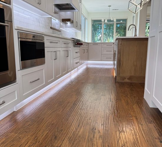 Modern kitchen featuring custom cabinetry, stainless steel appliances, and a hardwood floor with under-cabinet lighting, emphasizing effective storage solutions and organization in kitchen remodeling.