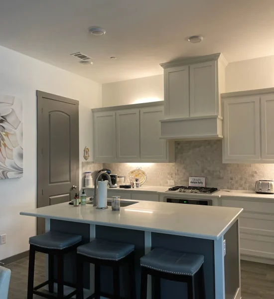Modern kitchen featuring light cabinetry, quartz countertop, and bar stools, illustrating functionality and style for countertop selection in home design.