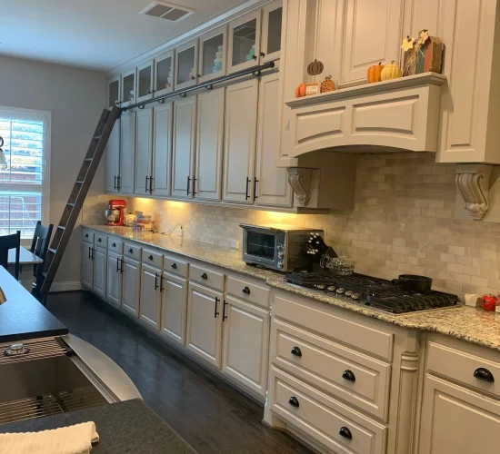 Modern kitchen featuring elegant cabinetry, granite countertops, stainless steel appliances, and a decorative ladder for upper storage access, emphasizing functionality and style in home design.
